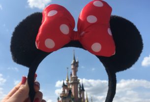 Une personne tenant a couronne de Minnie Mouse au-dessus de la tour de Disneyland Paris.