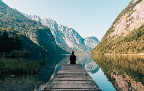 Un homme en pleine méditation près d'un lac.