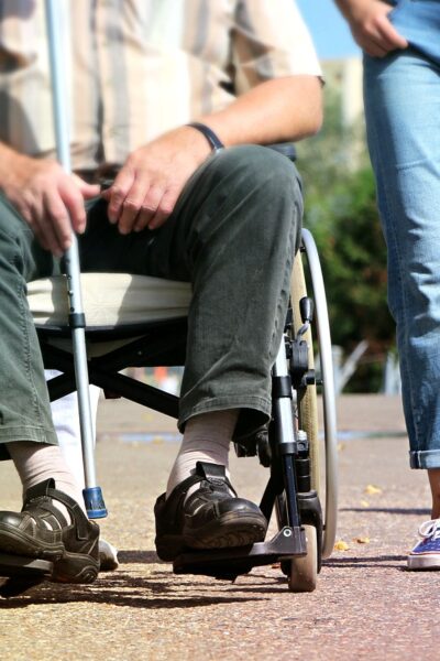 Une personne en fauteuil roulant aidée par une jeune fille.
